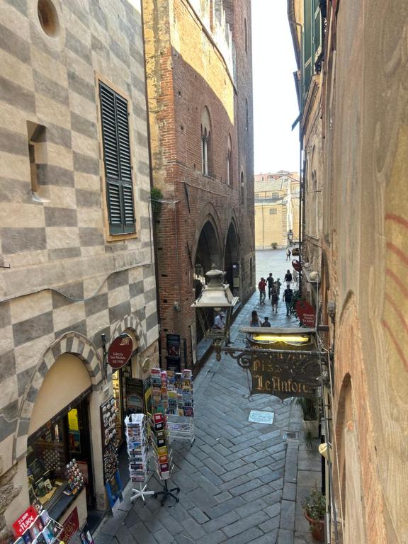 une ruelle dans un immeuble avec des gens marchant dans la rue dans l'établissement Affittacamere Bernardo Ricci, à Albenga