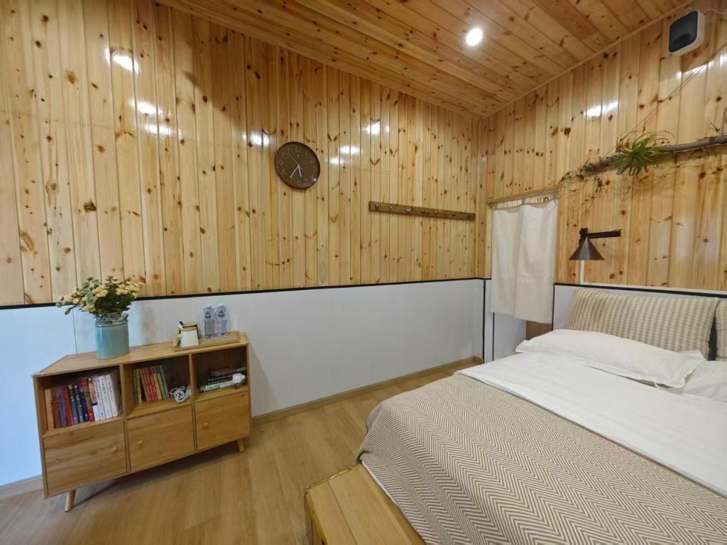 a bedroom with a bed and a wooden wall at Leshan Qiuye Book House B&B in Leshan