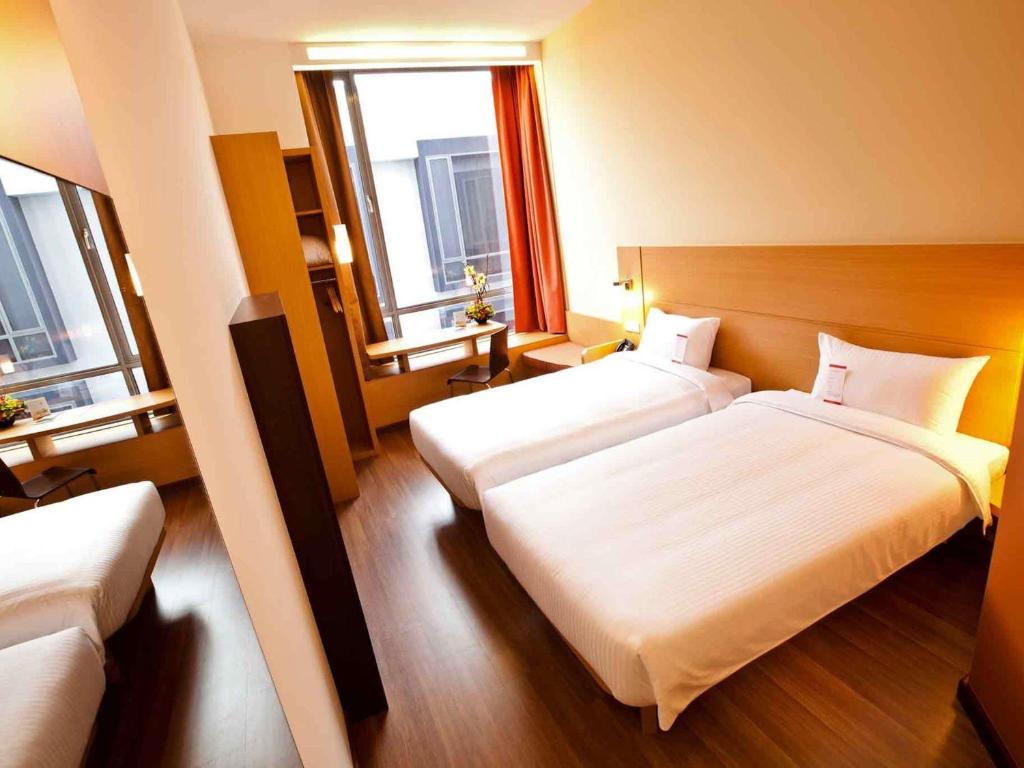 a hotel room with two beds and two windows at Ibis Singapore Novena in Singapore