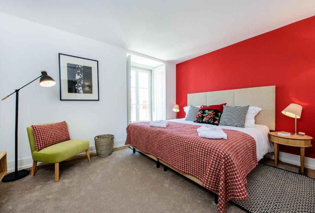 a red bedroom with a bed and a chair at Martinhal Lisbon Chiado in Lisbon