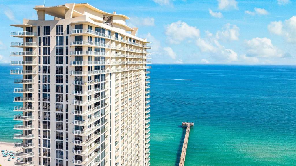 a rendering of a tall building next to the ocean at Luxurious 2BD Condo with Direct Ocean Views & Resort Pool in Sunny Isles in Sunny Isles Beach