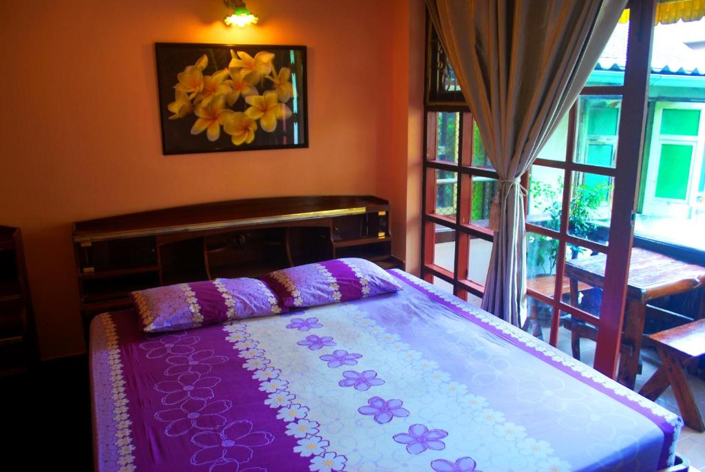 een slaapkamer met een bed met paarse lakens en een raam bij Pailin Guest House in Bangkok