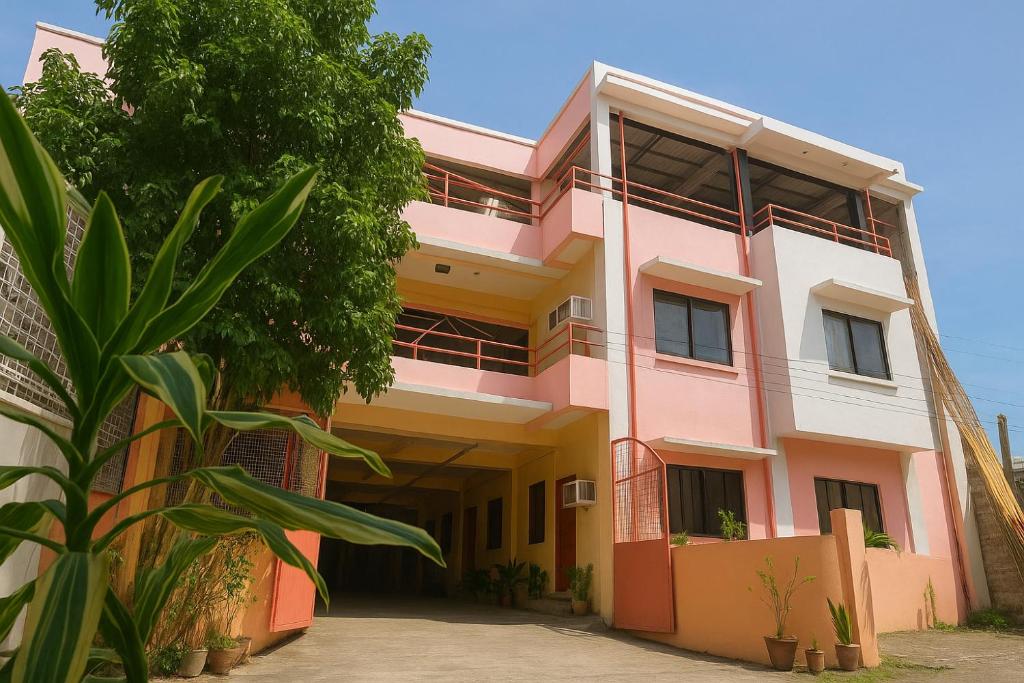 ein rosafarbenes Gebäude mit Bäumen davor in der Unterkunft Iloilo Transient Rooms in Iloilo City