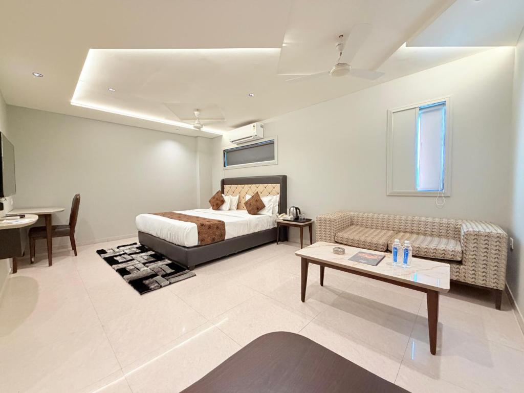 a bedroom with a bed and a couch and a table at Hotel Nova Vista in Rajkot