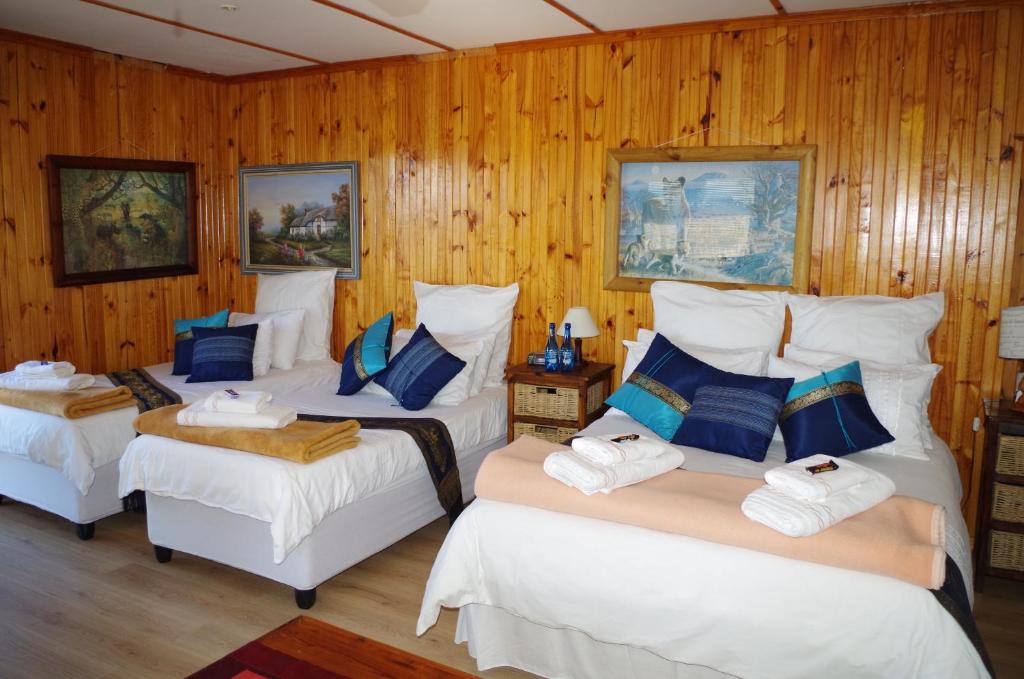 3 Betten in einem Zimmer mit Holzwänden in der Unterkunft Tertia's Logcabin in Port Alfred