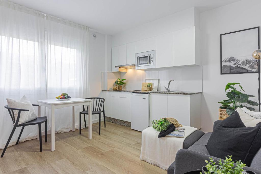 a white living room with a table and a kitchen at Terreo 10-12 in A Coruña