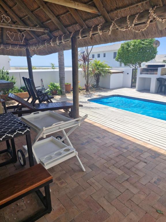 a patio with a table and chairs and a swimming pool at Beachway on Golden Mile in St. Helena Bay