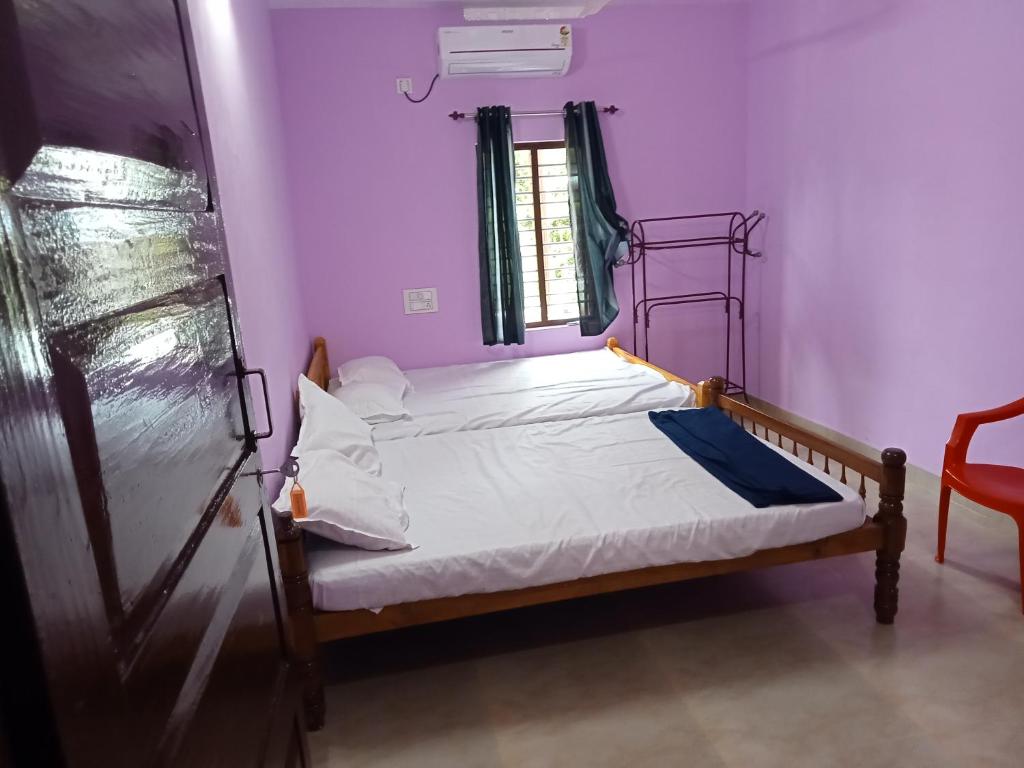 Un dormitorio con una cama en una habitación con paredes moradas. en Ashabhavan, en Varkala
