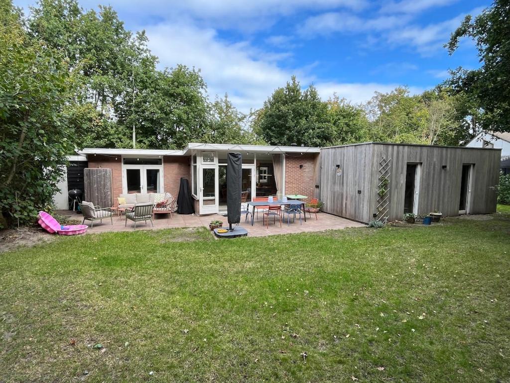 a small house with a patio and a yard at Fraaie familiebungalow op heerlijk rustige plek in Ouddorp