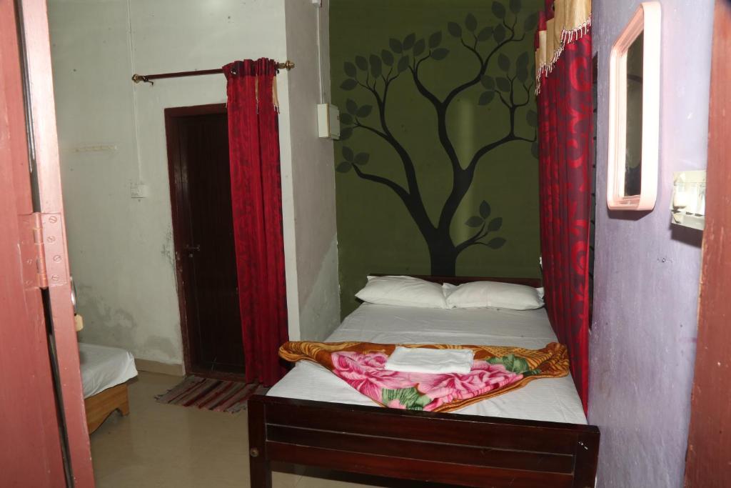 a bedroom with a bed with a tree mural on the wall at Snow drops homestay in Kallar Vattiyar
