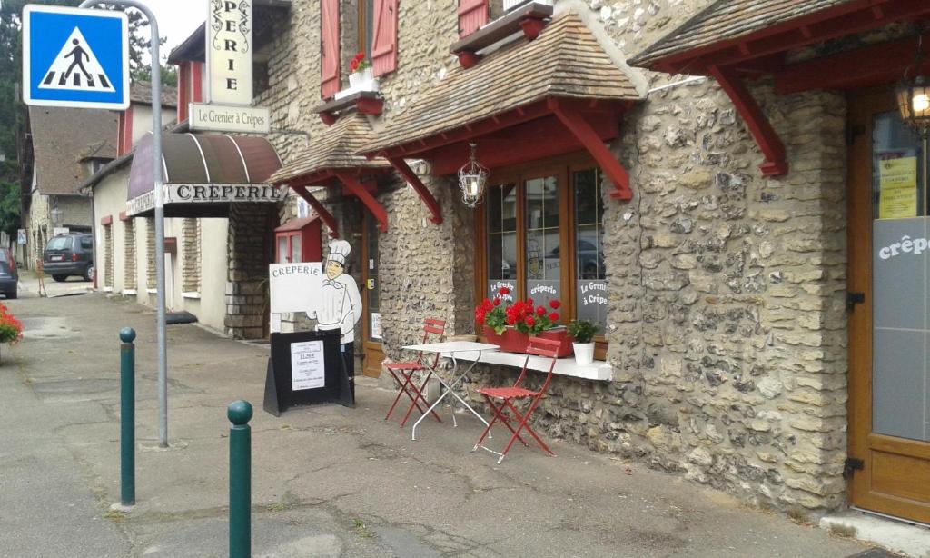 une table et des chaises à l'extérieur d'un bâtiment dans l'établissement Le Grenier A Crepes, à Saint-Aquilin-de-Pacy