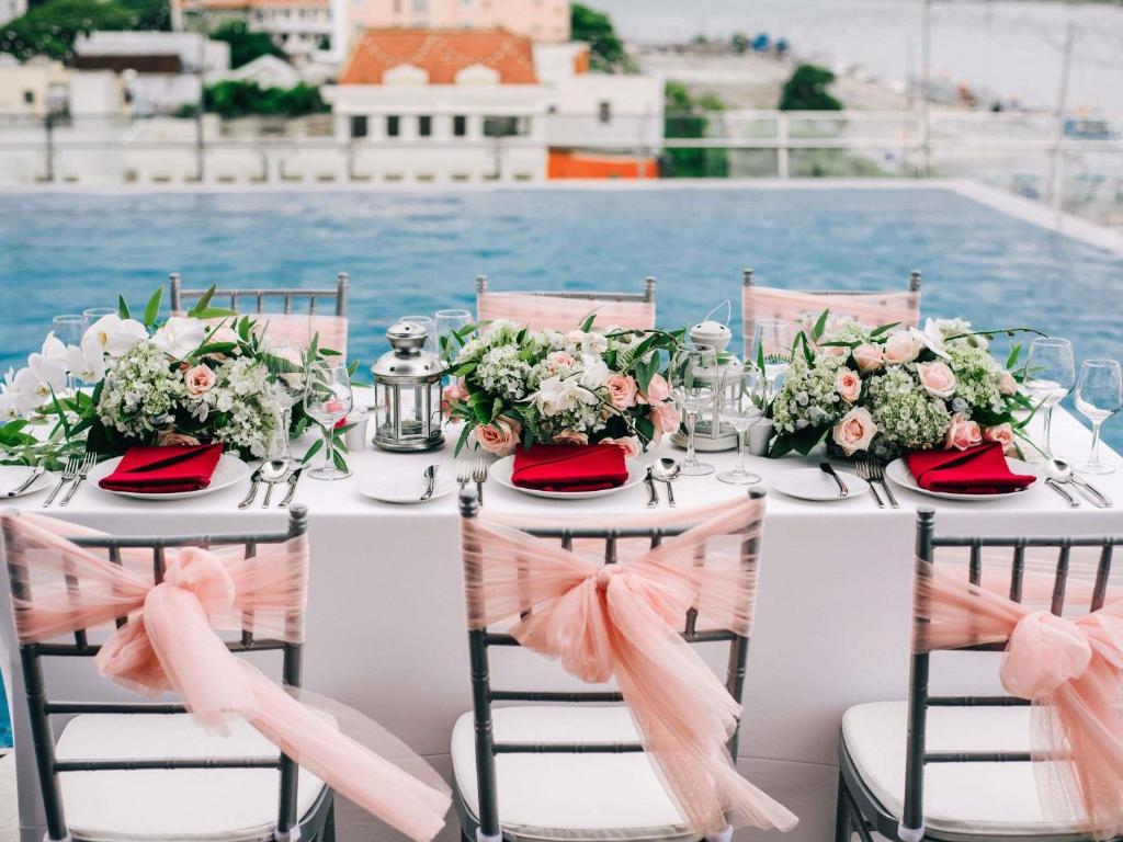 A formal banquet table arranged beside the pool with floral centerpieces and pink chair bows.