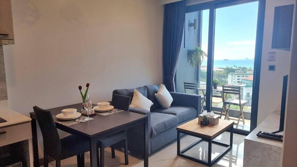 Una sala de estar con un sofá azul y una mesa. en Silk Ao Nang Condominium, en Ao Nang Beach