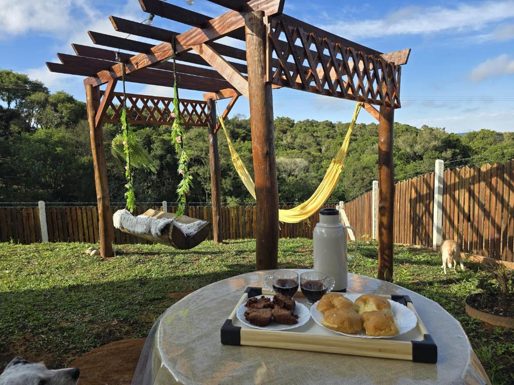 a table with a plate of food and a hammock at Cabana Sol Poente PR in São José dos Pinhais