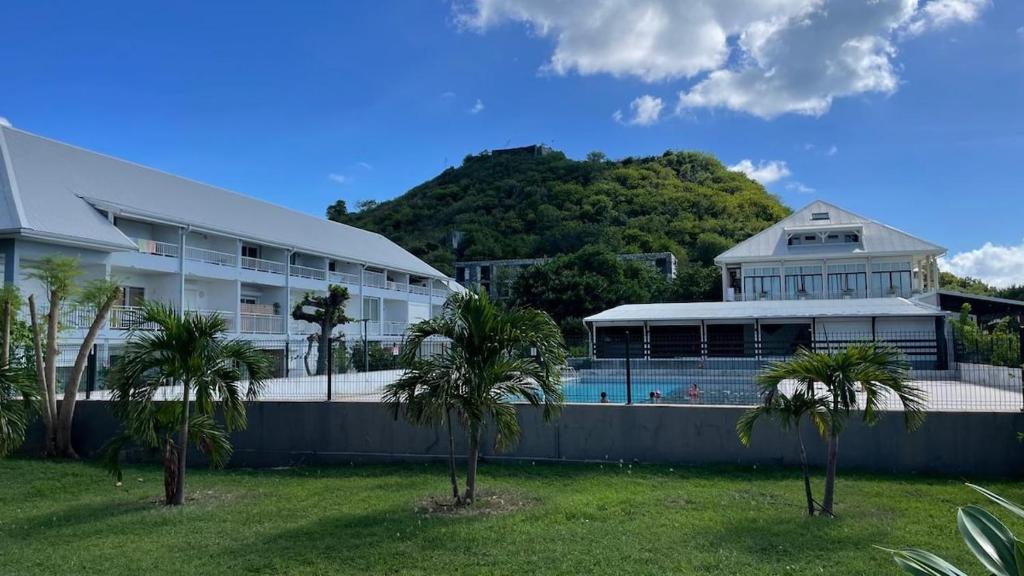 a large building with a swimming pool and palm trees at Beachfront Studio in Marigot