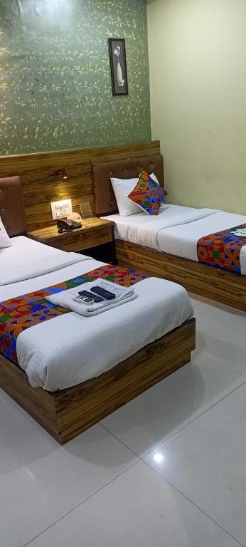 two beds in a room with two tables at Orange International-SANTACRUZ in Mumbai