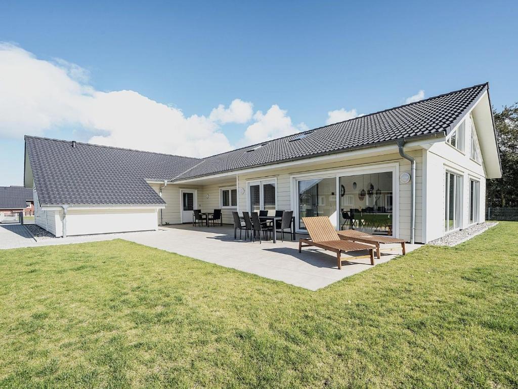 une maison avec un patio avec une table et des chaises dans l'établissement Nordseehaus für Gruppen - hell, modern, komfortabel, à Dagebüll