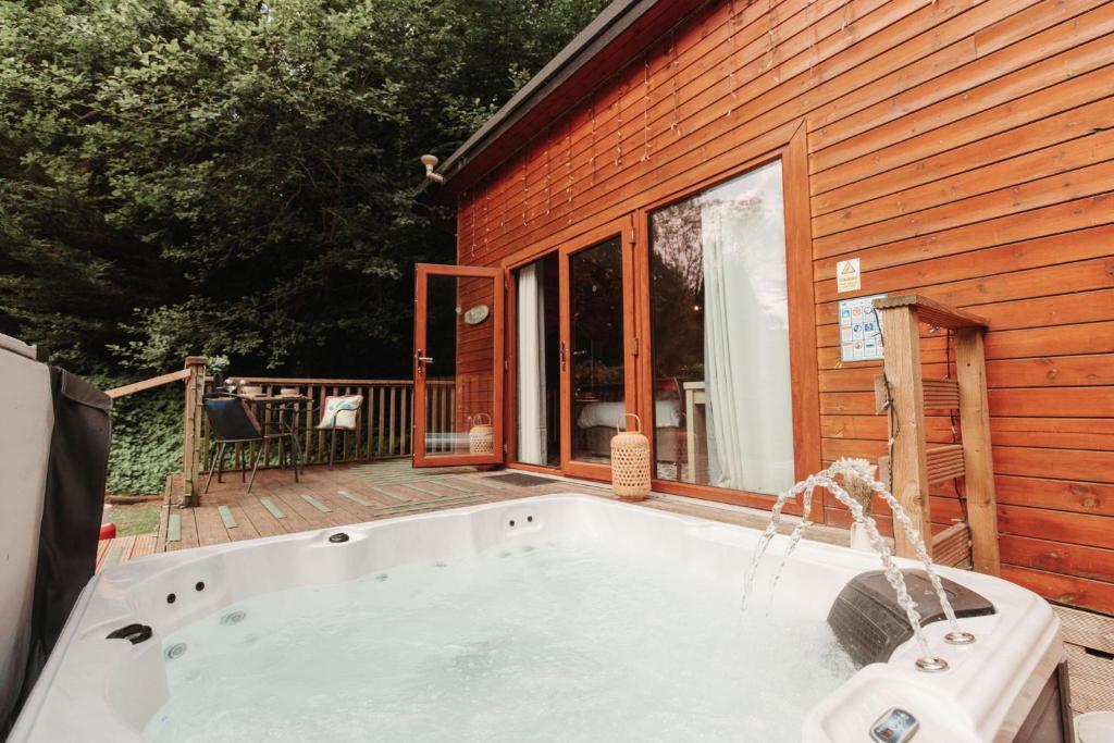 a hot tub on a deck next to a house at Robin Woodside Lodge in Caerwys