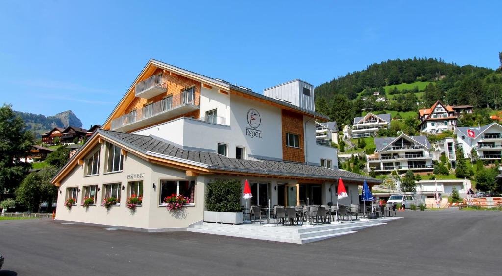 a building with tables and chairs in a parking lot at Hotel Espen in Engelberg