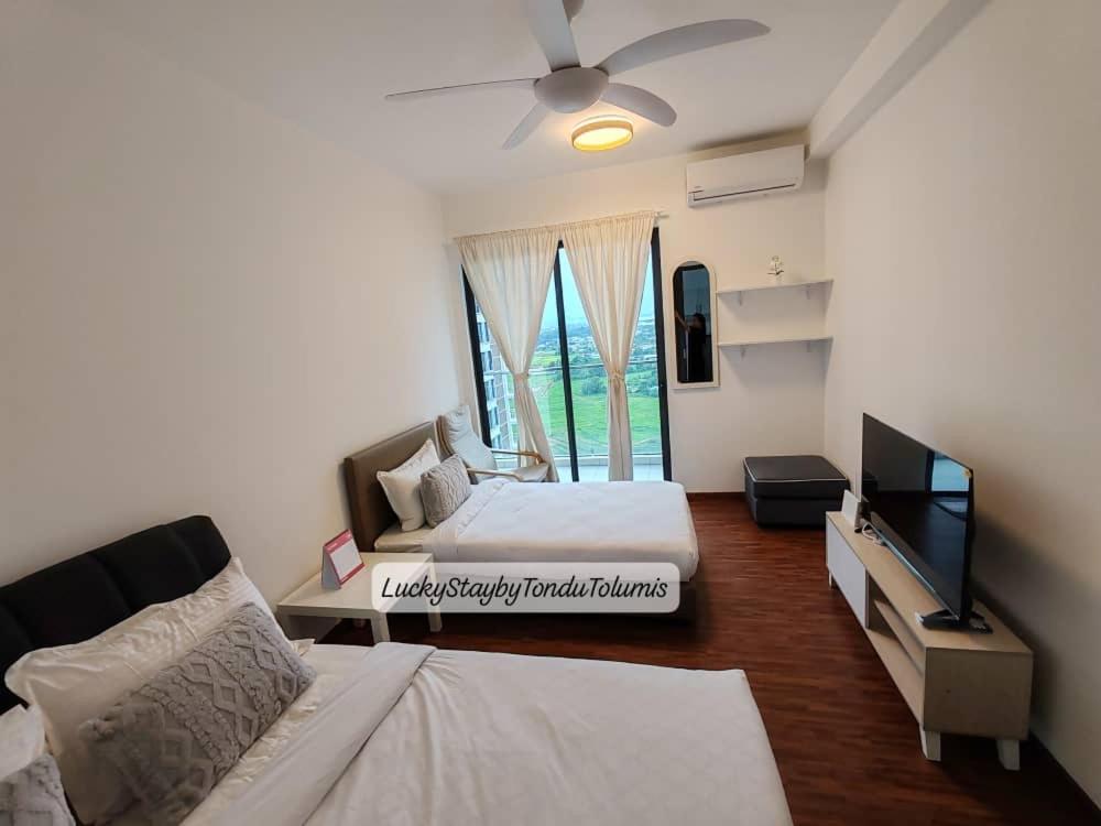 a bedroom with two beds and a flat screen tv at K Avenue Lucky Stay Suite in Penampang