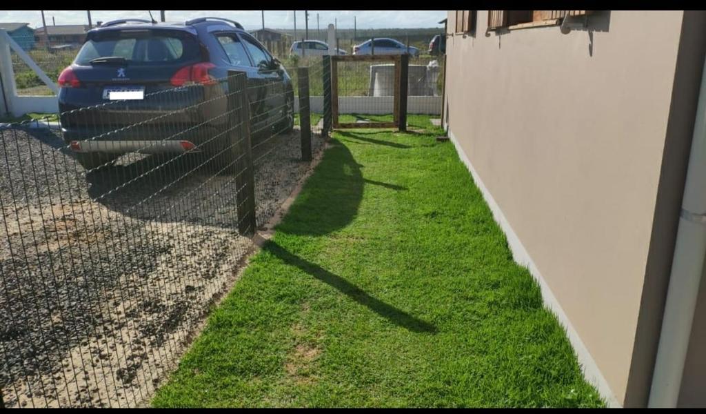a fence with a car parked in a yard at Casa Beira-mar da Sumaré in Balneário Gaivotas