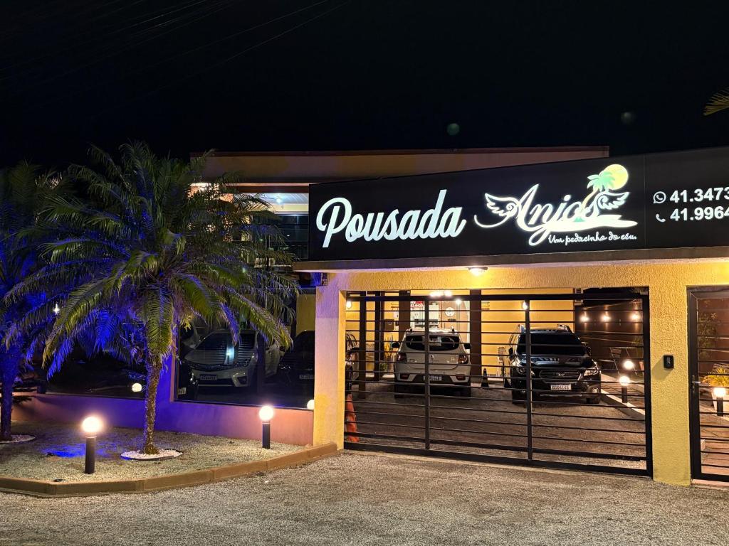 a car dealership with a palm tree in front of it at Pousada Anjos - à 2 quadras do mar in Matinhos