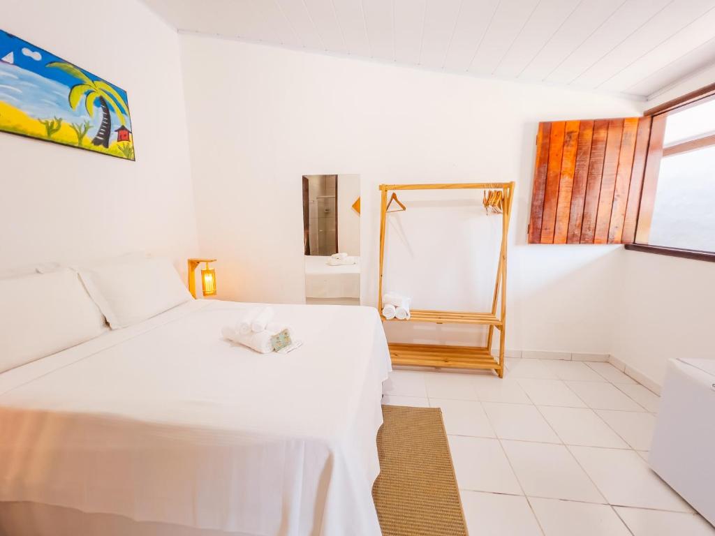 a bedroom with a white bed and a mirror at Pousada do Enildo in São Miguel dos Milagres