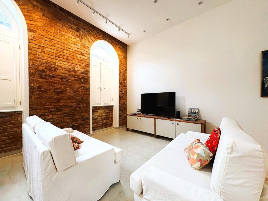 sala de estar con 2 sofás blancos y TV en Casa Maravilhosa no Coração de Santa Teresa, en Río de Janeiro