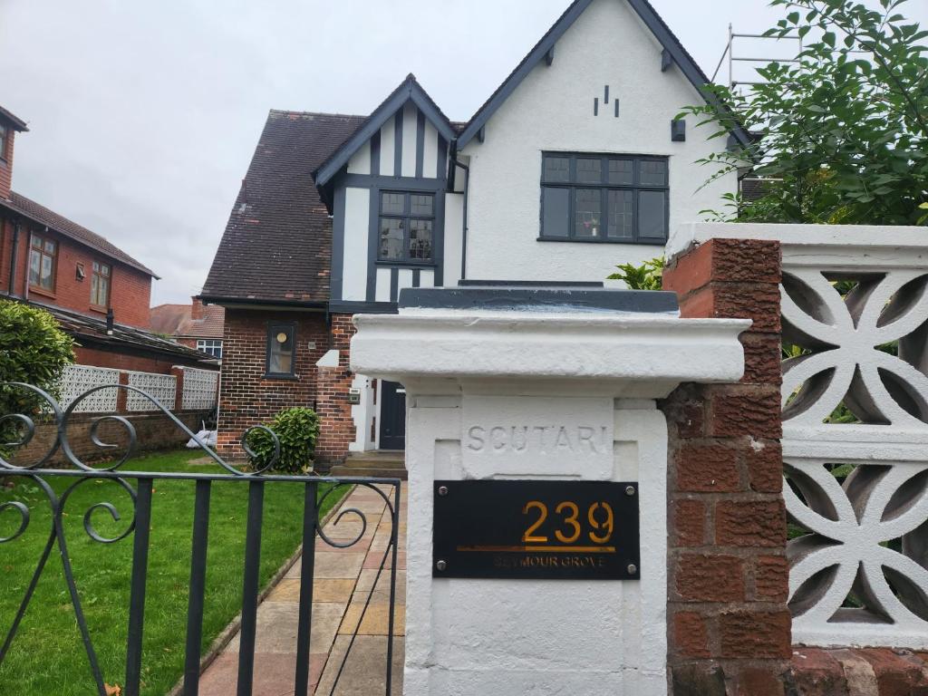 een huis met een hek met een bord erop bij Luxury Cottage Stay Rooms Free Wifi Old Trafford Manchester in Manchester