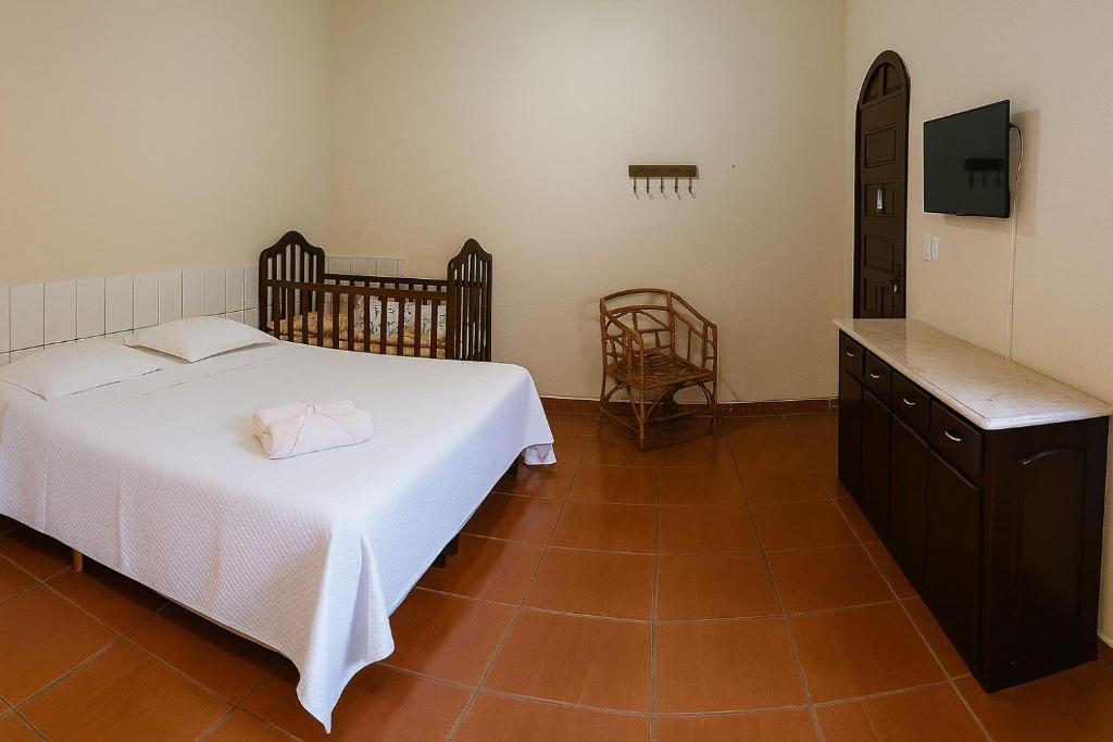 a bedroom with a white bed and a wooden floor at Estância Pontello - próximo ao aeroporto de Confins in Confins