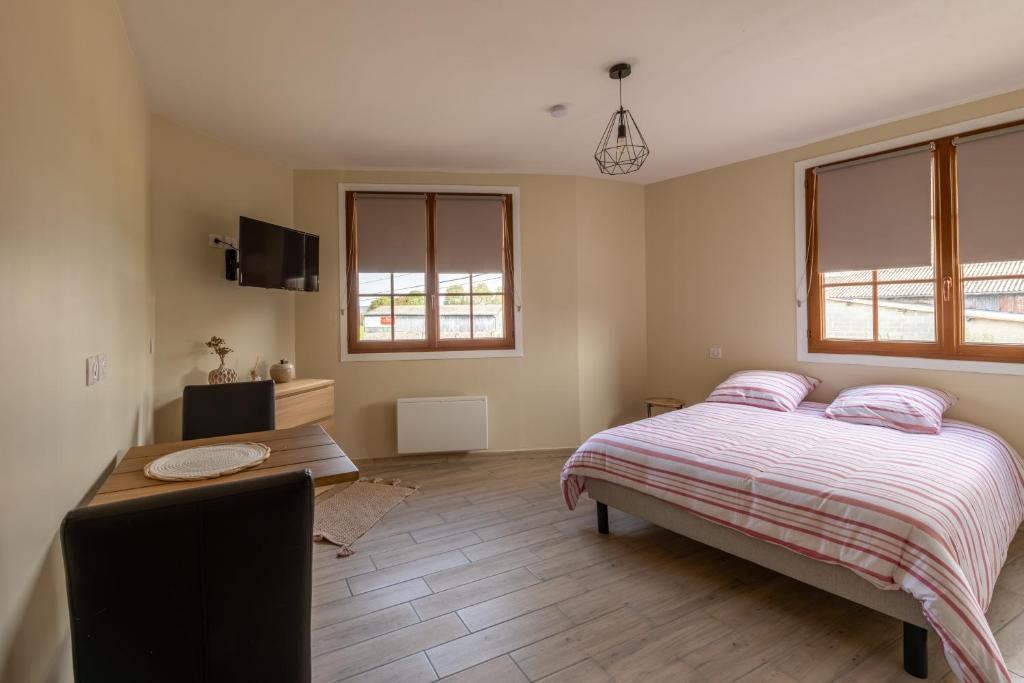 Un dormitorio con una cama y un escritorio y dos ventanas. en Le Reflet de l'Horizon - Proche Plage, en Le Bois de Cise