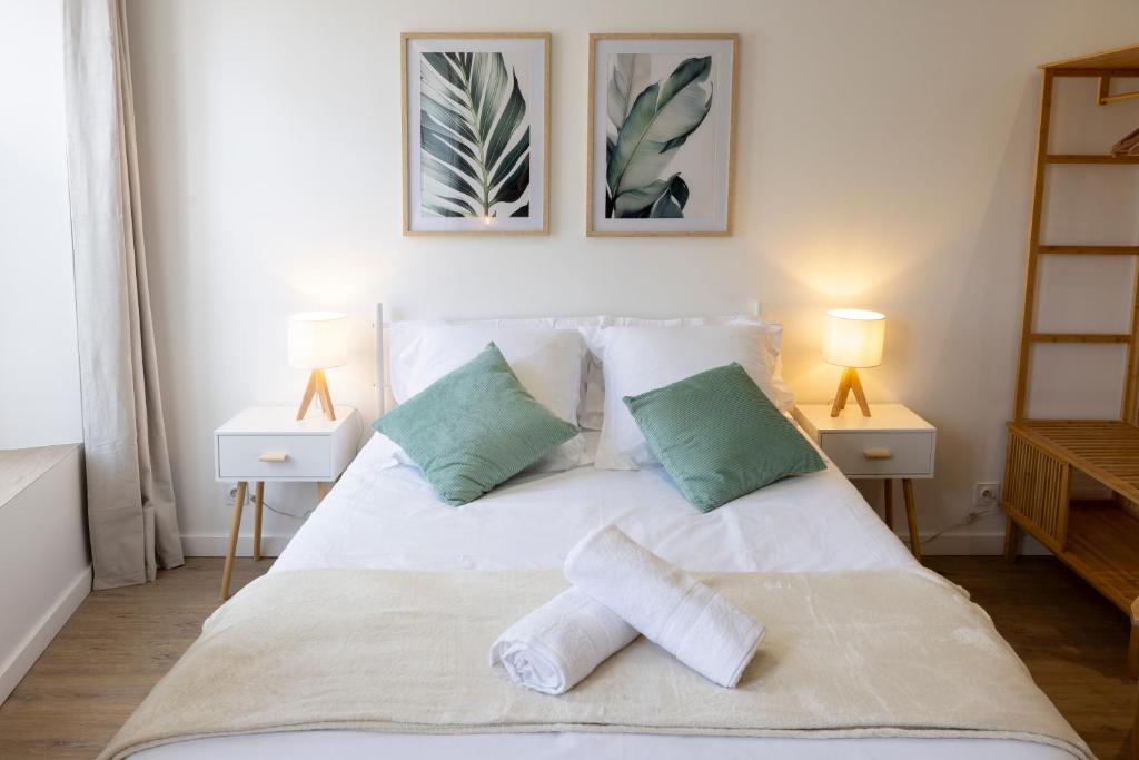 a bedroom with a white bed with two lamps at Le Vert Olivier- Studio tout confort in Montluçon