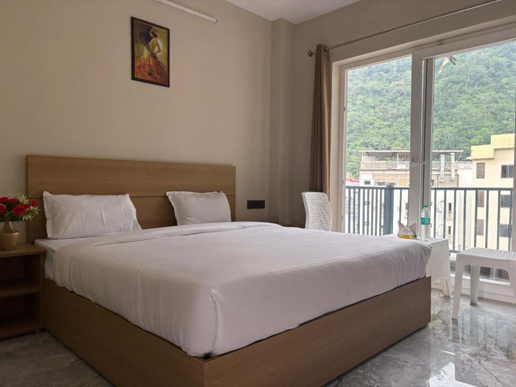 a bedroom with a large bed and a large window at Hotel Abline the Oaks in Rishīkesh