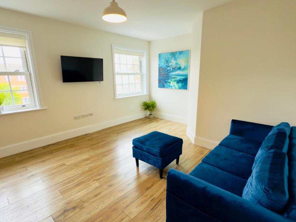 a living room with a blue couch and a tv at Union Apartment - Light and Airy in Bedford