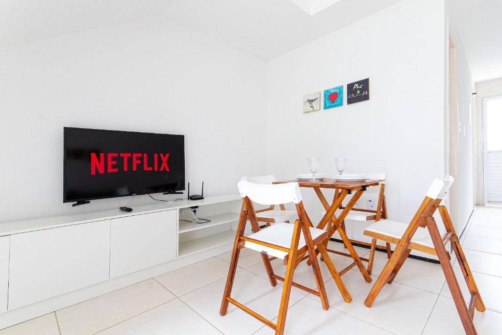 a living room with a tv and a table and chairs at Beach Townhouses - Porto das Dunas By Carpediem in Mangabeira