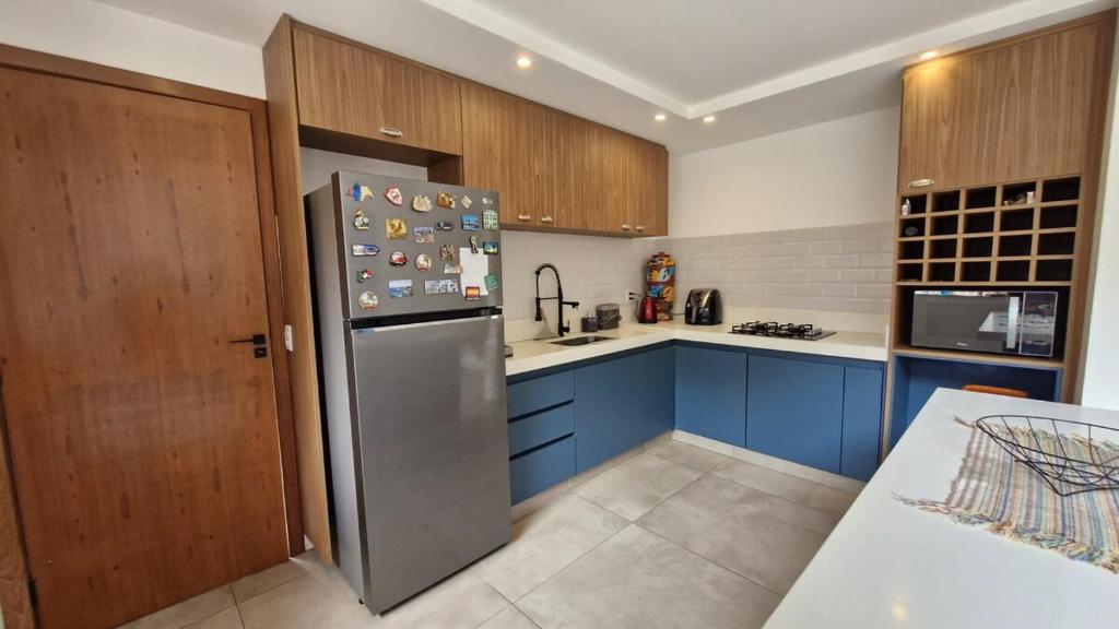 La cuisine est équipée de placards bleus et d'un réfrigérateur en acier inoxydable. dans l'établissement Casa shizen, à Nova Friburgo