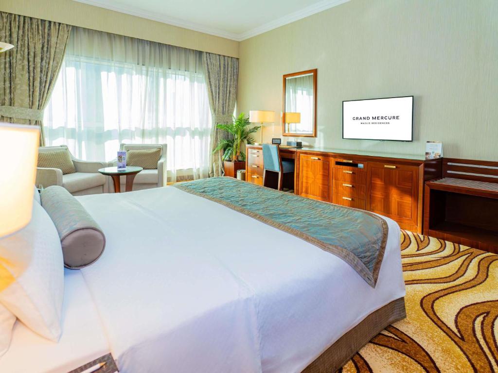 a hotel room with a large bed and a television at Grand Mercure Majlis Residences Abu Dhabi in Abu Dhabi
