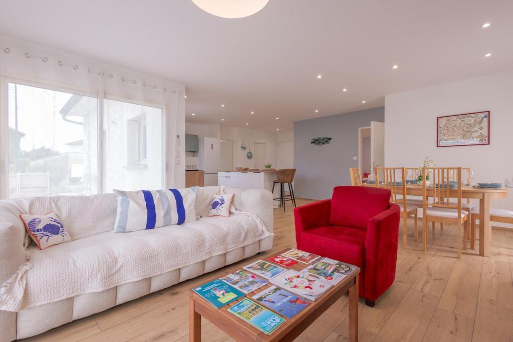 a living room with a white couch and a red chair at Villa au coeur de Mézériat in Mézériat