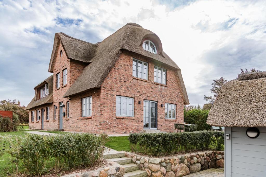 an old brick house with a thatched roof at Haus Deichblick 1 in Dunsum