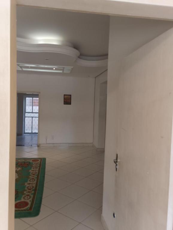 an empty room with white walls and a green rug at Quarto 01 in Montes Claros