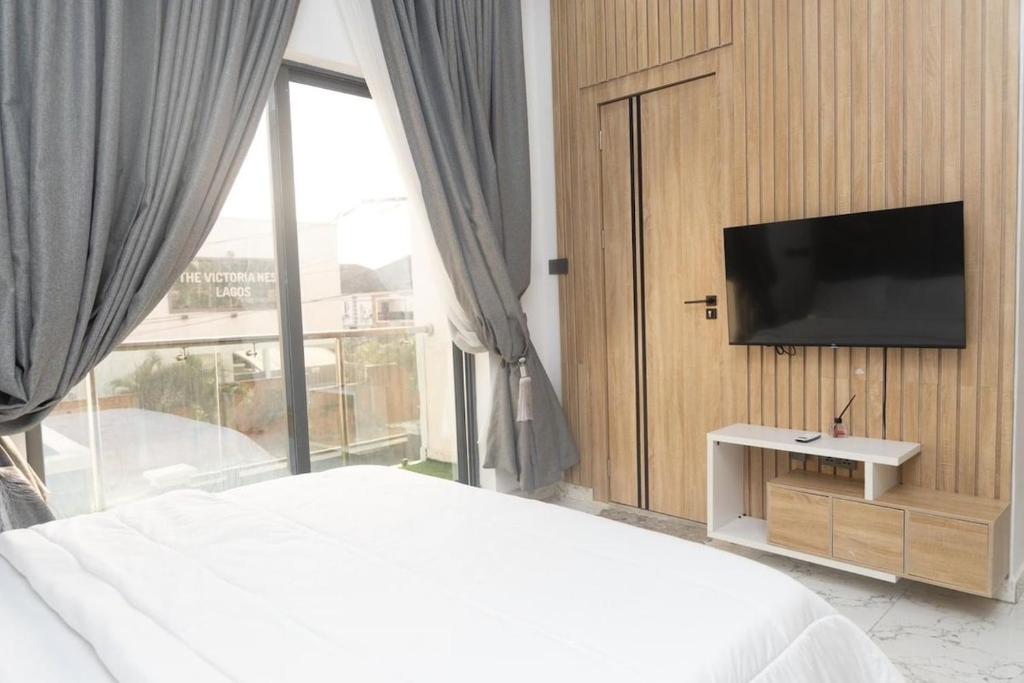 a bedroom with a bed and a flat screen tv at Luxury 3BR Apt w balcony view in Chevron, Lekki in Lekki