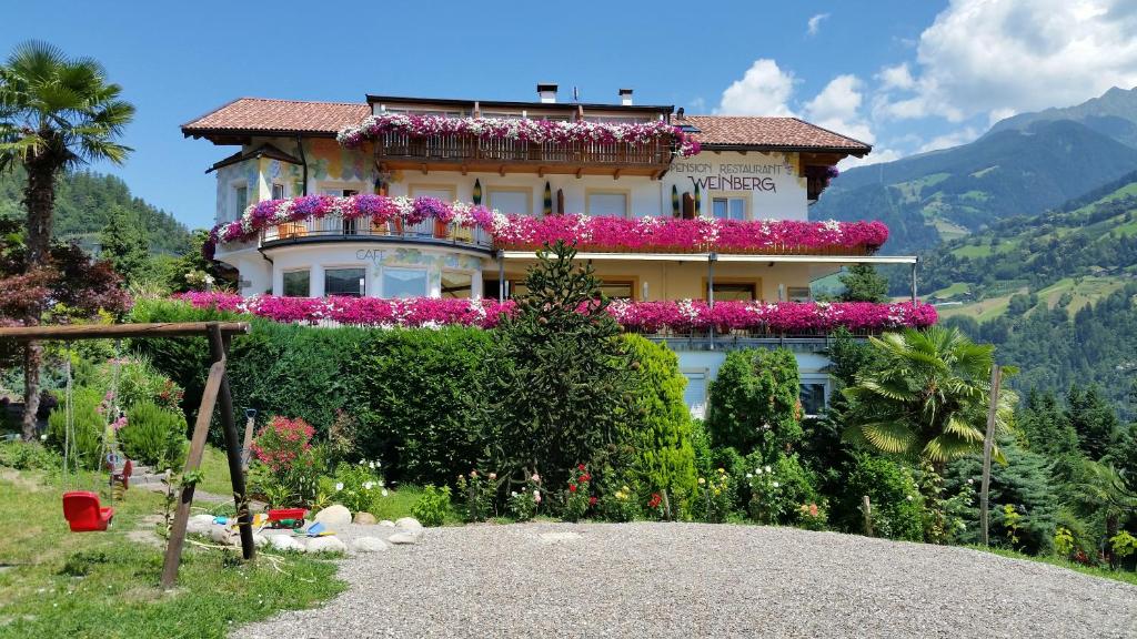 un edificio con flores a un lado. en Pension Weinberg, en Rifiano