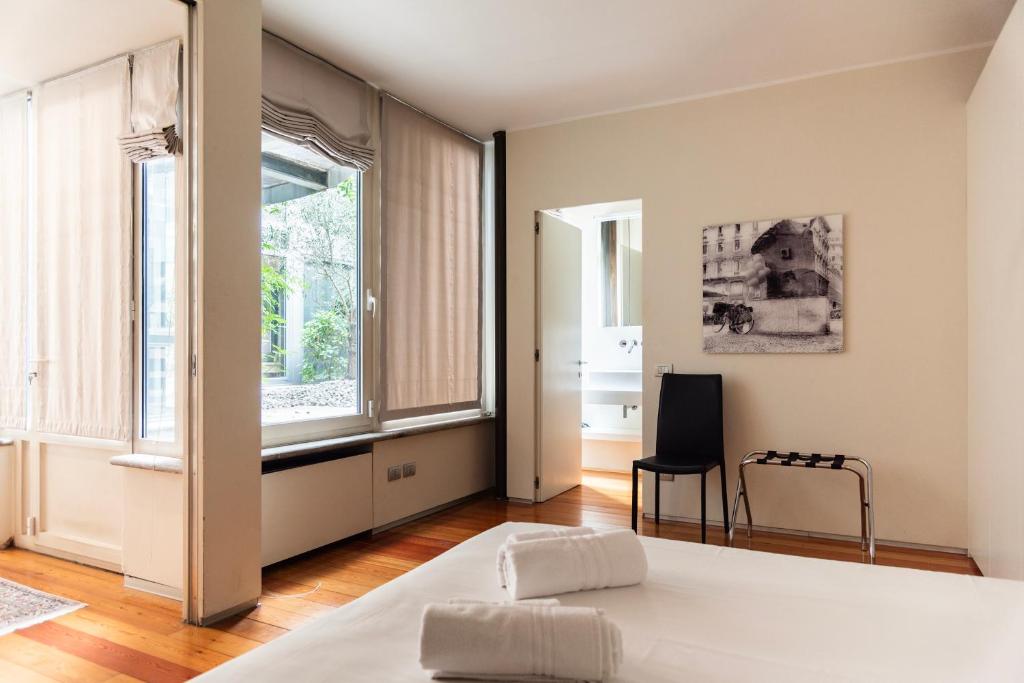une chambre avec un lit, une chaise et des fenêtres dans l'établissement YouHosty - Luxury Town House, à Milan