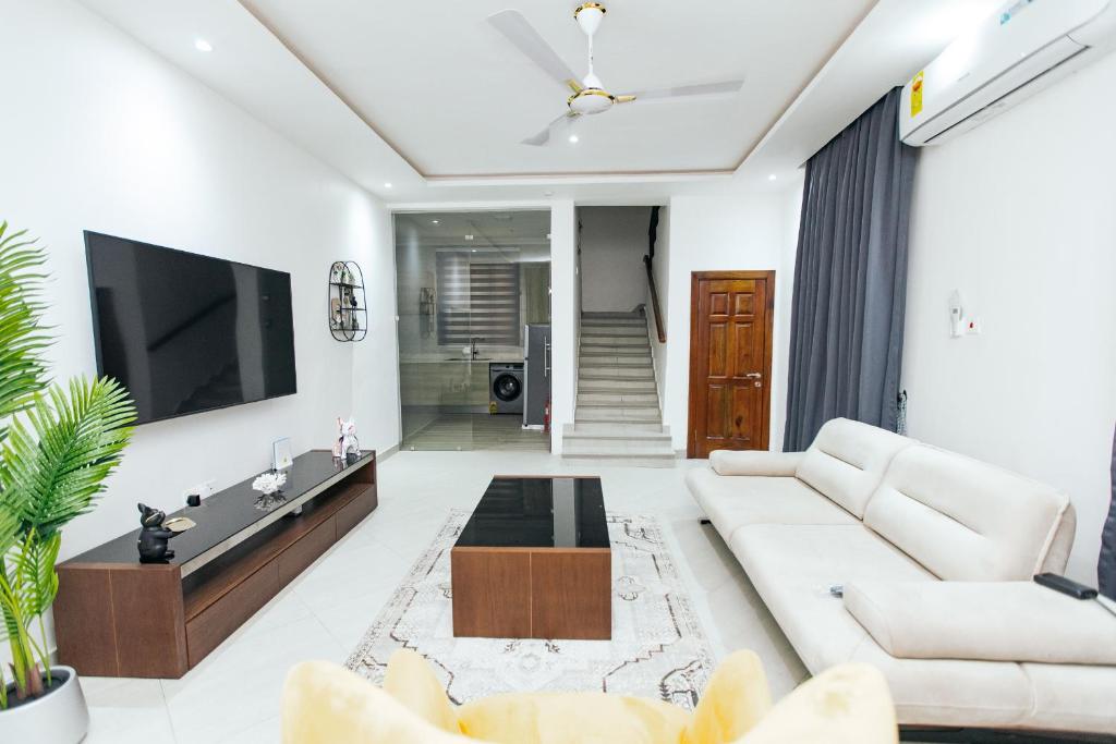 a living room with a white couch and a tv at Luxurious townhouse behind Achimota Mall in Accra
