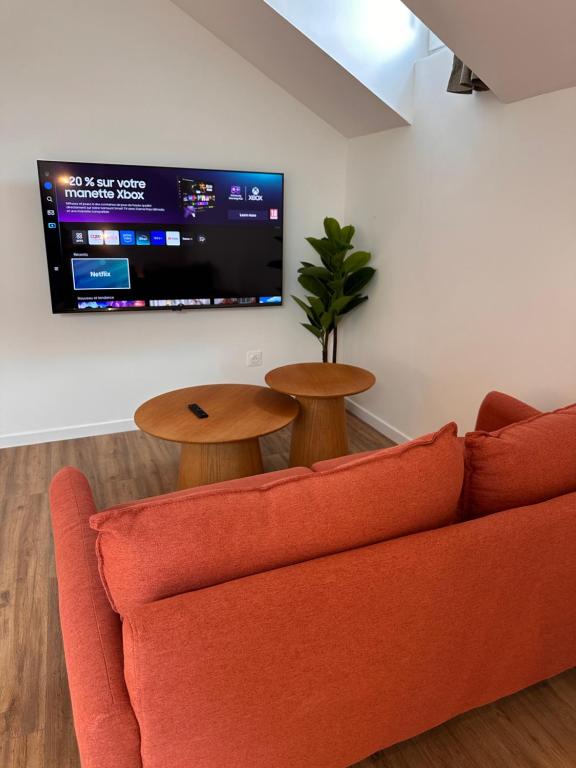 ein Wohnzimmer mit einem orangenen Sofa und einem Flachbild-TV in der Unterkunft Tendance & Confort à Perigueux in Périgueux