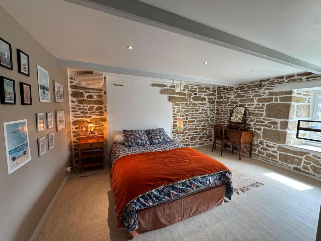 a bedroom with a bed and a stone wall at Ty Guillerm - Maison bretonne entre terre et mer in Plounévez-Lochrist