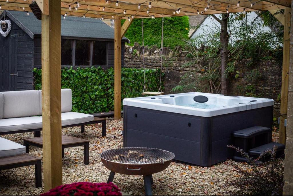 - un bain à remous dans une cour avec une pergola dans l'établissement The Old Pen Cottage, à Leafield