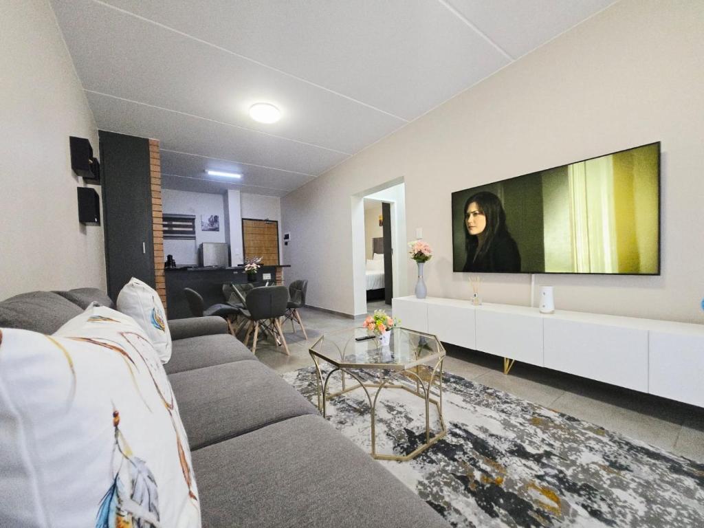 a living room with a couch and a tv on a wall at Nat's Villa in Midrand