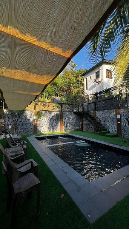 a swimming pool with chairs under a large umbrella at Staycation with Swimming Pool Lipa Batangas in Palavit
