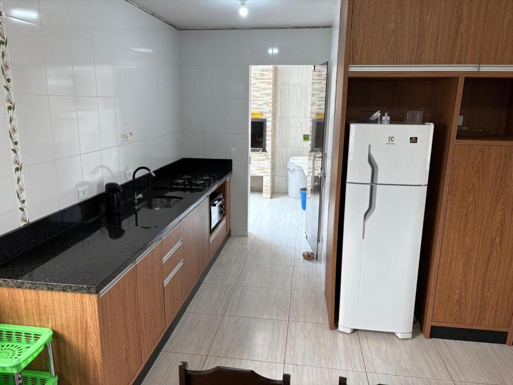 a kitchen with a white refrigerator and a sink at apartamento lindo com 2 quartos in Itapoa